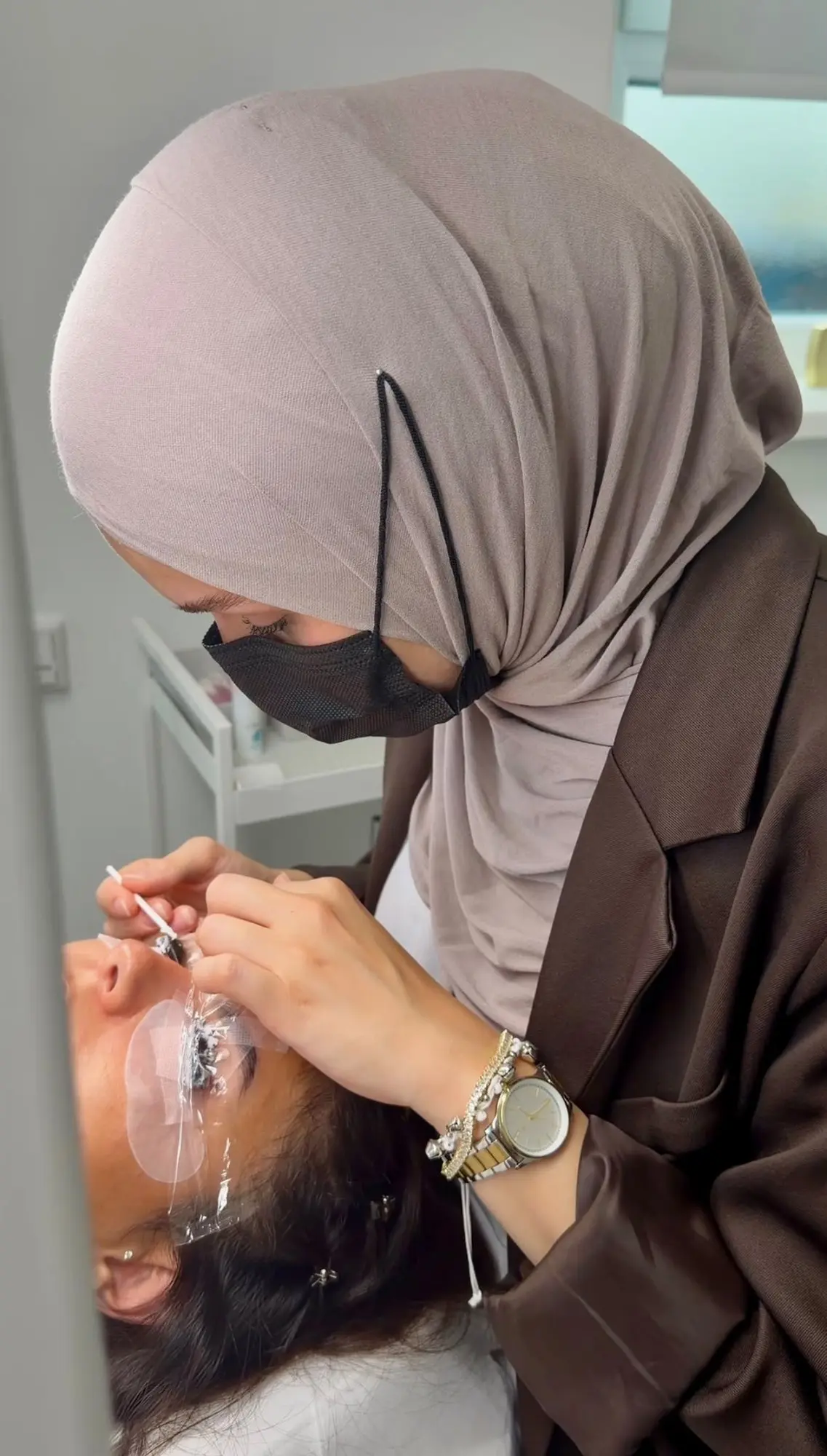 Dilşad richtet mit einem Stäbchen die Wimpern einer liegenden Kundin auf dem Silikonpad aus
