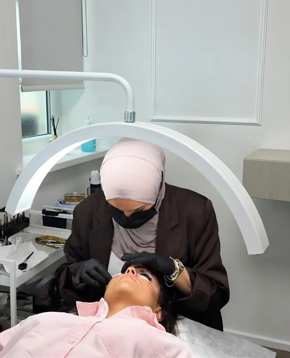 Blick ins Studio: Dilşad arbeitet unter der Bogenleuchte an den Wimpern einer liegenden Kundin